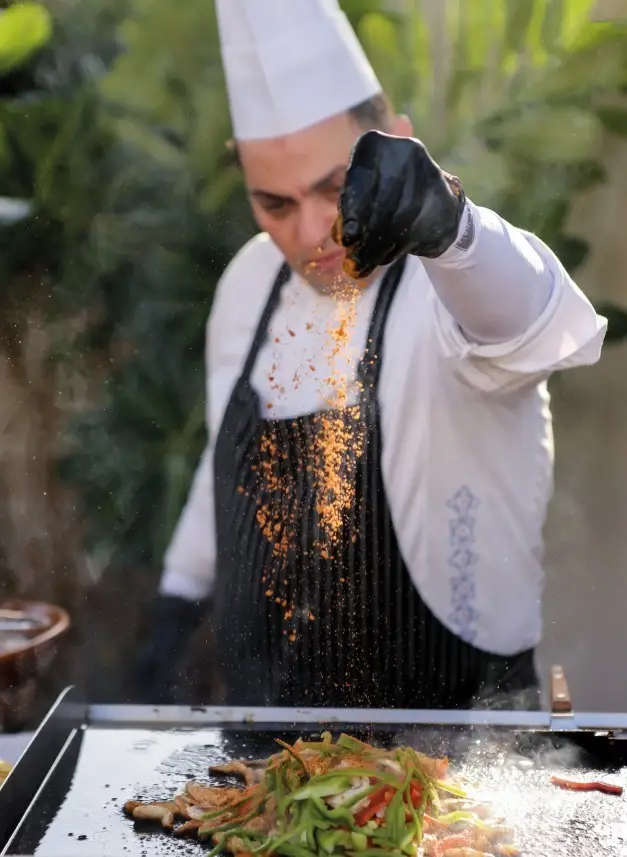 the cook pours seasoning into the food